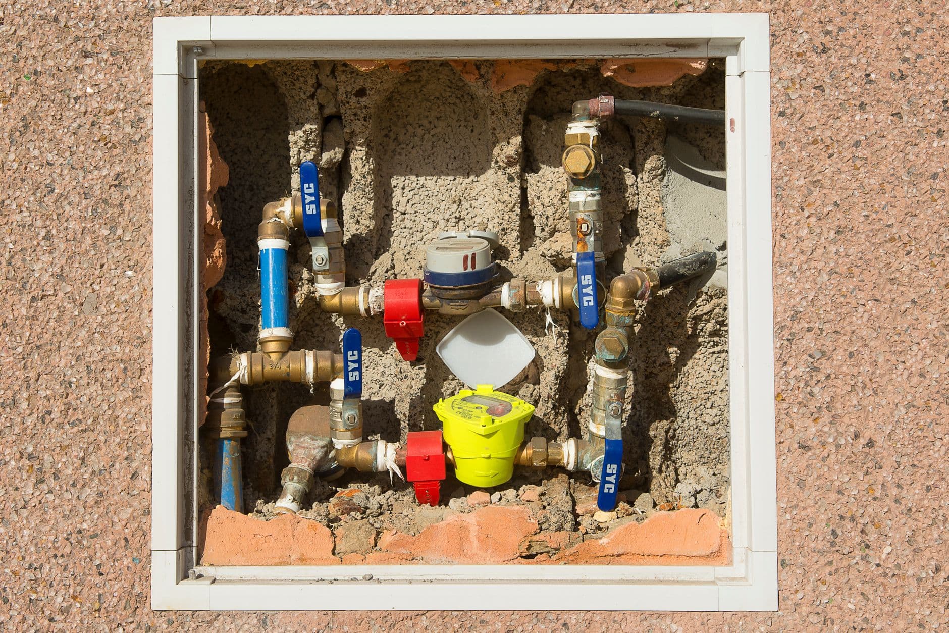 Contadores y tuberías de agua en el portal de un edificio